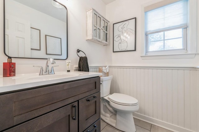 bathroom featuring tile patterned floors, wainscoting, toilet, and vanity