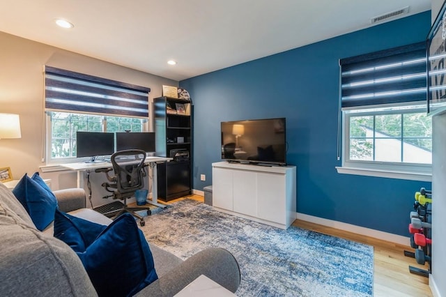 home office featuring visible vents, a healthy amount of sunlight, light wood-style flooring, and baseboards