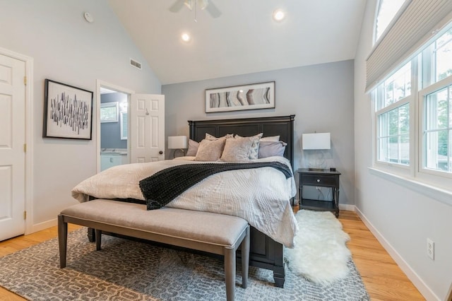 bedroom with connected bathroom, baseboards, high vaulted ceiling, and light wood finished floors
