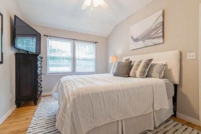 bedroom with light wood-style flooring, baseboards, lofted ceiling, and ceiling fan