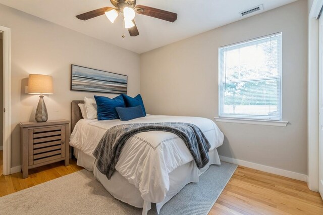 bedroom featuring visible vents, ceiling fan, baseboards, and wood finished floors