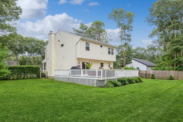 back of property with a deck, a yard, fence, and a chimney