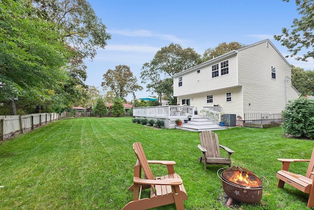 rear view of house with a wooden deck, an outdoor fire pit, central AC unit, a yard, and a fenced backyard