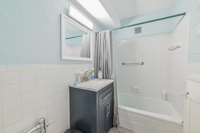 8900 170th St Unit 7N, Jamaica, NY 11432 - full bathroom featuring vanity, visible vents, shower / tub combo, wainscoting, and tile walls