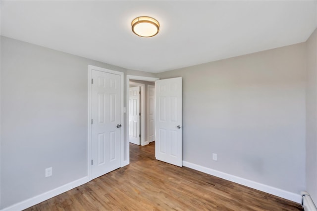 7 Howard Ave, Freeport, NY 11520 - unfurnished bedroom with baseboards, baseboard heating, and light wood-style flooring