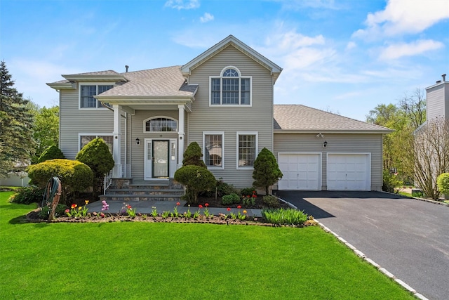 view of front of house with an attached garage, a shingled roof, a front yard, and aphalt driveway