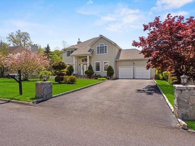 traditional-style house with aphalt driveway, an attached garage, and a front yard