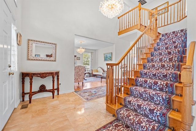 entryway featuring stairway, a chandelier, visible vents, and a towering ceiling