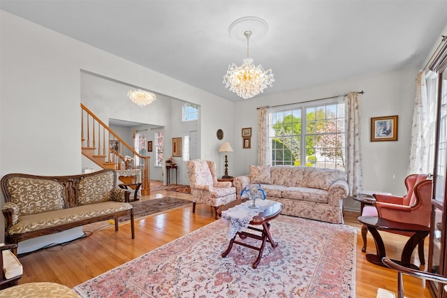 living room with stairs, a chandelier, and wood finished floors