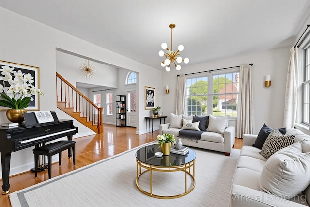living area with a notable chandelier, stairway, and wood finished floors