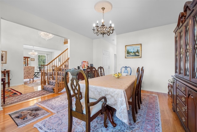 dining area featuring baseboards, stairs, a notable chandelier, and light wood-style floors
