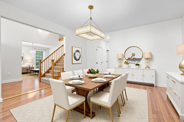 dining area with light wood-style flooring, stairs, a notable chandelier, and baseboards