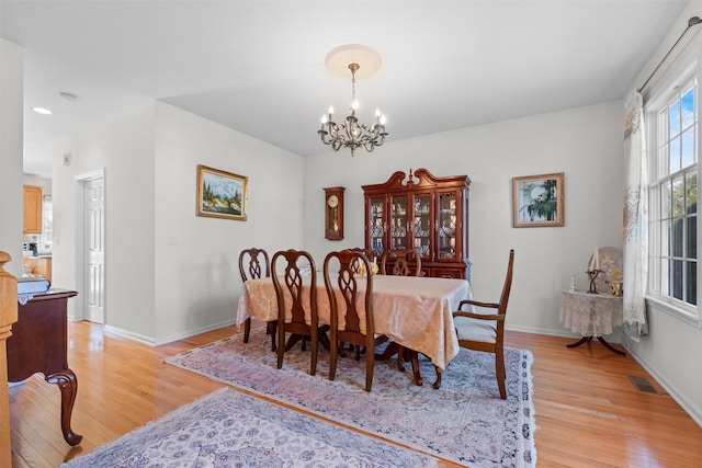 dining area featuring baseboards, a notable chandelier, light wood-style flooring, and visible vents