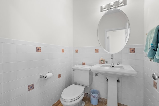 bathroom featuring toilet, tile walls, and wainscoting