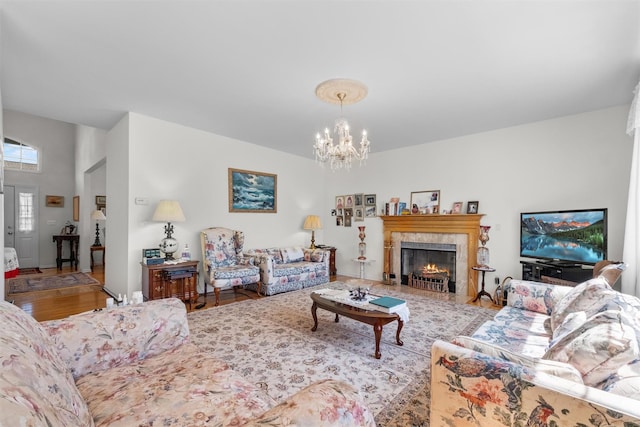 living area with a fireplace, a chandelier, and wood finished floors