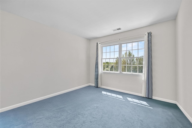 carpeted spare room with visible vents and baseboards