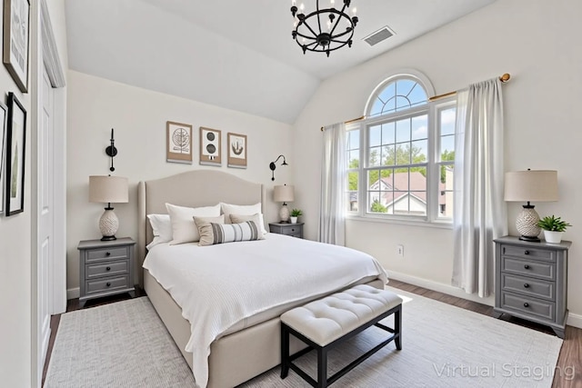 bedroom with wood finished floors, visible vents, baseboards, a chandelier, and lofted ceiling