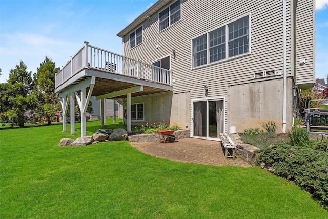 rear view of property with a lawn, a wooden deck, and a patio