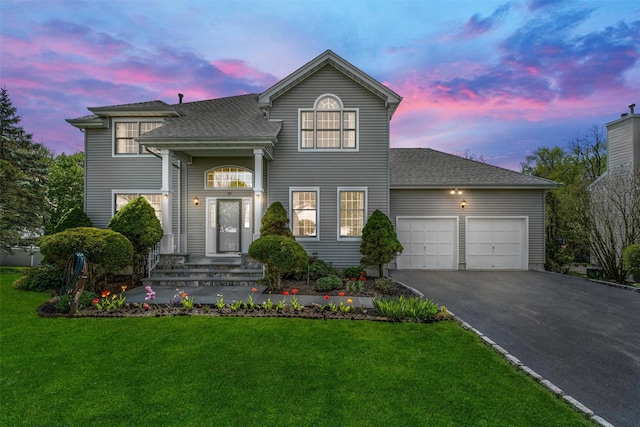 view of front facade featuring an attached garage, a shingled roof, a yard, and driveway