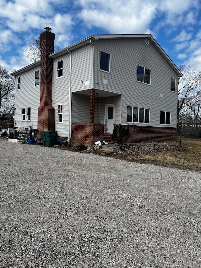 rear view of property featuring brick siding and a chimney