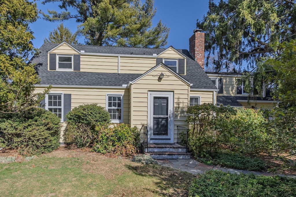 17 Dogwood Dr, Stony Brook, NY 11790 - view of front facade with a chimney, a shingled roof, and a front lawn