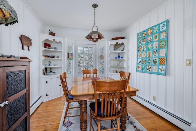 dining area with ornamental molding, light wood finished floors, and a baseboard radiator