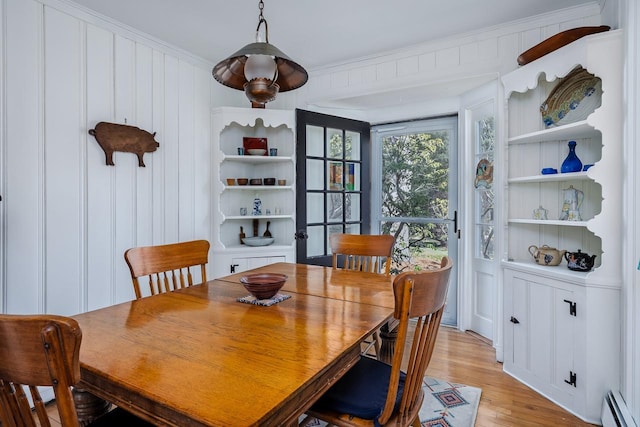 dining space featuring ornamental molding, light wood finished floors, and a baseboard heating unit