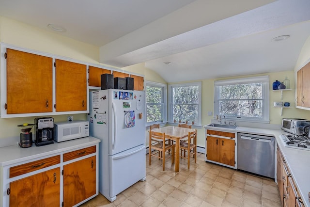 kitchen featuring a sink, white appliances, light countertops, brown cabinetry, and vaulted ceiling