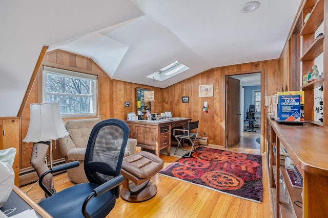 home office with wooden walls, lofted ceiling with skylight, and light wood-style flooring