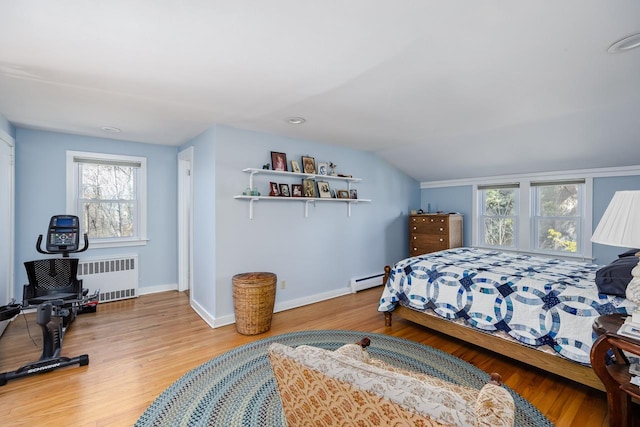 bedroom with radiator heating unit, baseboards, vaulted ceiling, and wood finished floors