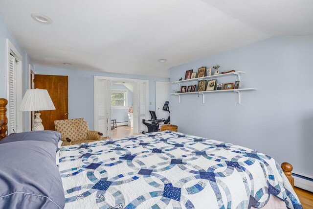 bedroom with a baseboard radiator, recessed lighting, and wood finished floors