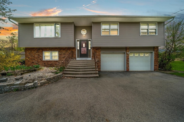 bi-level home featuring brick siding, aphalt driveway, and a garage