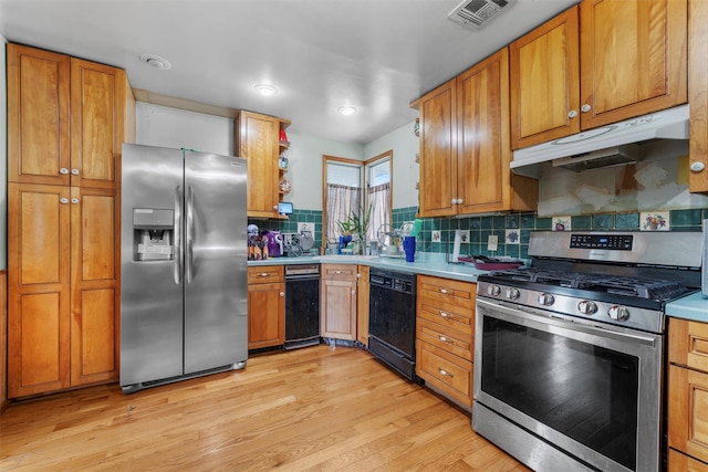 kitchen featuring light countertops, stainless steel appliances, tasteful backsplash, under cabinet range hood, and visible vents