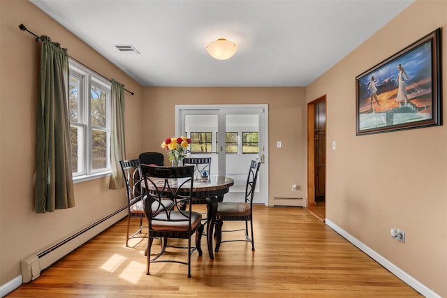 dining area featuring light wood-style floors, baseboards, a baseboard radiator, and visible vents