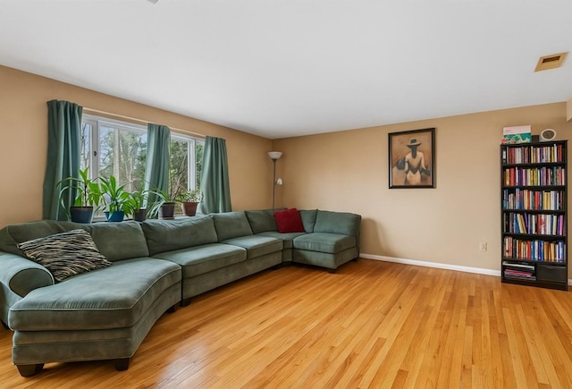 living area featuring baseboards, light wood-style flooring, and visible vents