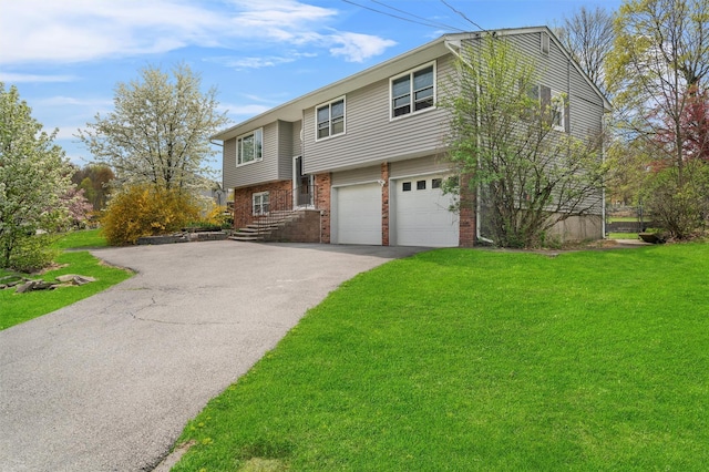 split foyer home featuring a garage, driveway, a front lawn, and brick siding
