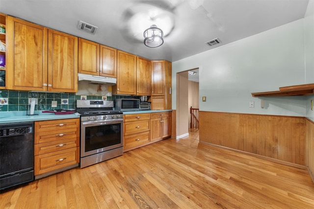 kitchen featuring visible vents, wainscoting, light wood-style floors, under cabinet range hood, and appliances with stainless steel finishes