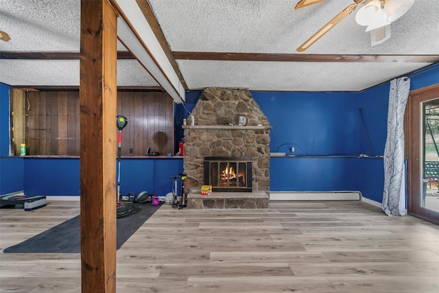 unfurnished living room featuring a textured ceiling, ceiling fan, a baseboard heating unit, and beam ceiling