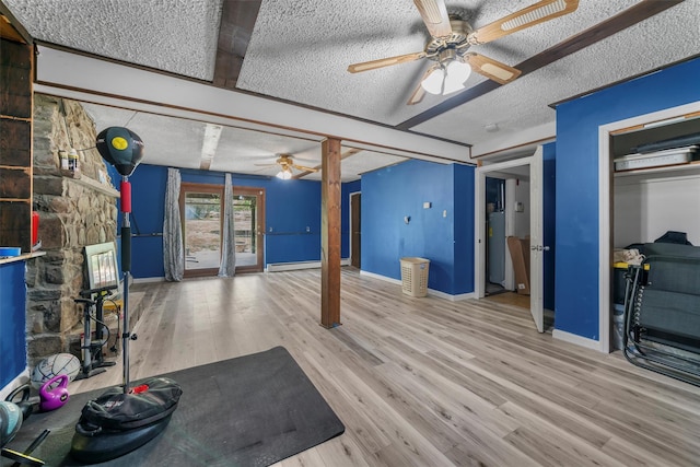 exercise room featuring baseboards, a ceiling fan, a textured ceiling, and wood finished floors