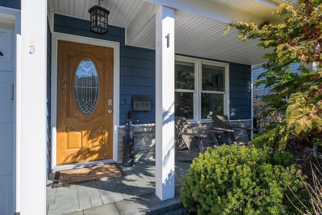 view of exterior entry with a porch and stone siding