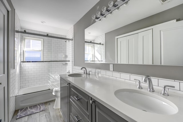 bathroom with enclosed tub / shower combo, toilet, wood finished floors, and a sink