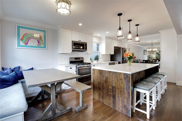 kitchen featuring stainless steel appliances, a breakfast bar, a sink, a kitchen island, and crown molding