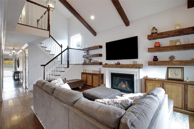 living room featuring beam ceiling, a towering ceiling, wood finished floors, stairs, and a fireplace