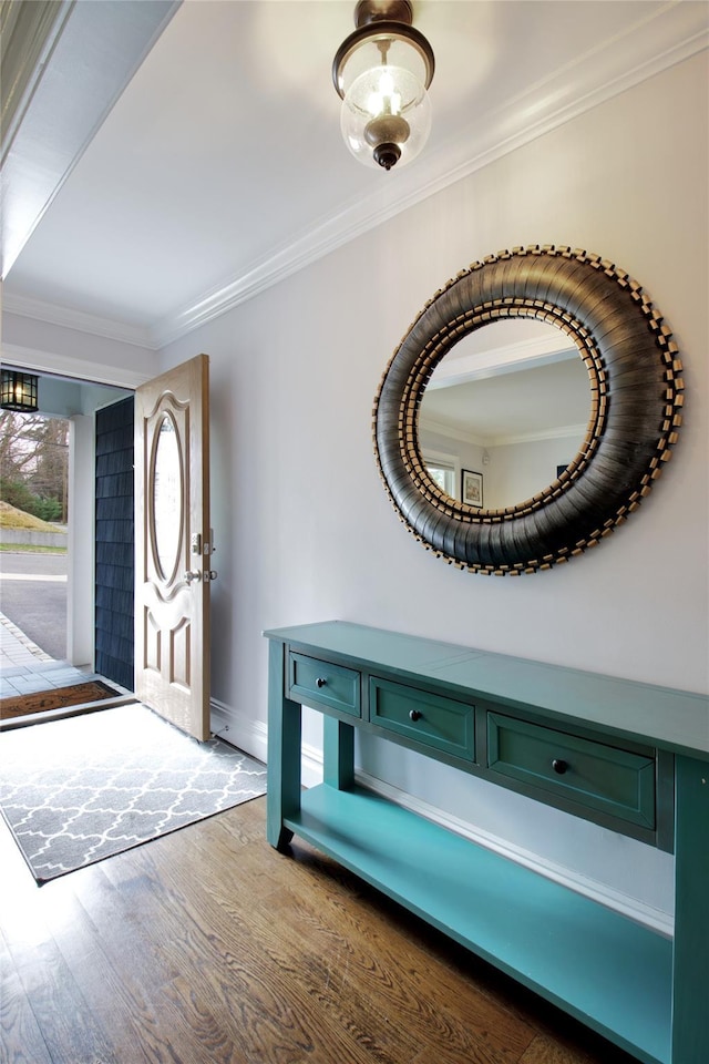 foyer entrance featuring wood finished floors, baseboards, and ornamental molding