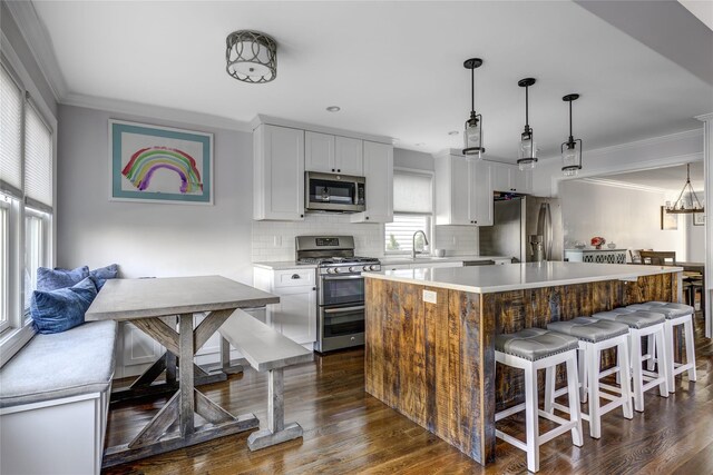 kitchen with ornamental molding, decorative backsplash, appliances with stainless steel finishes, and a sink