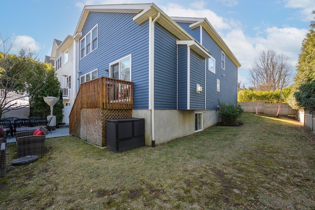 view of home's exterior with a lawn, fence, and a deck