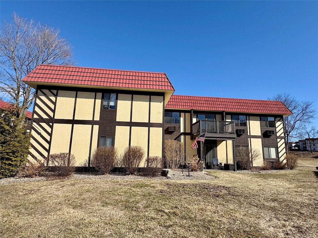 back of property with a balcony, a tiled roof, and stucco siding