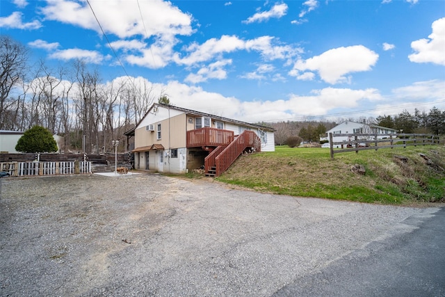 view of home's exterior featuring stairs, a yard, a wooden deck, and fence