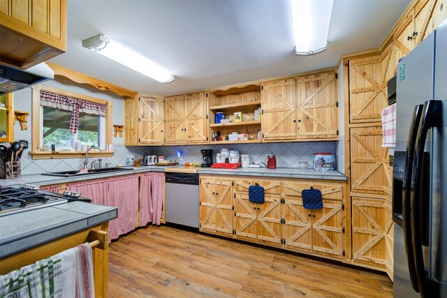 kitchen featuring fridge with ice dispenser, a sink, backsplash, tile countertops, and dishwasher