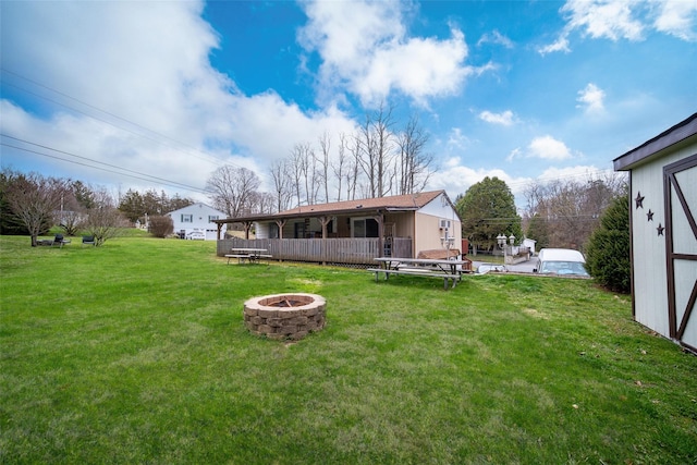 rear view of property with an outdoor fire pit and a yard